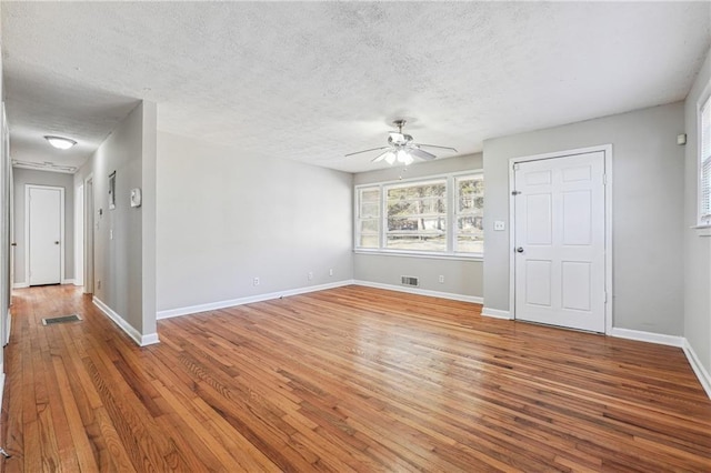 empty room with ceiling fan, wood-type flooring, and a textured ceiling