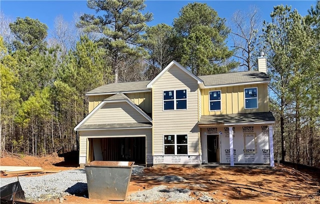 view of front facade featuring board and batten siding, a chimney, and a garage