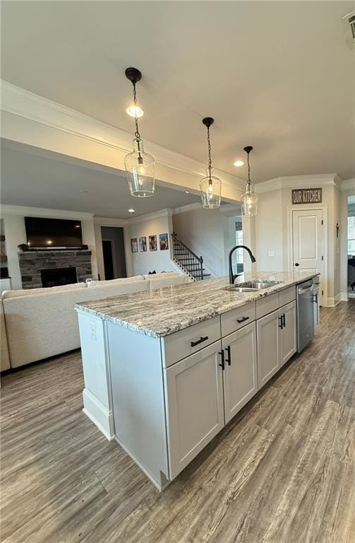 kitchen with white cabinetry, dishwasher, sink, hanging light fixtures, and a center island with sink