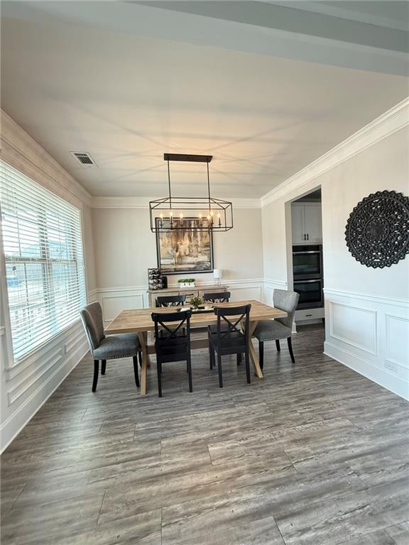 dining area with hardwood / wood-style floors, a notable chandelier, and ornamental molding