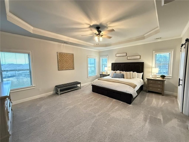 carpeted bedroom with ornamental molding, a barn door, ceiling fan, and a tray ceiling