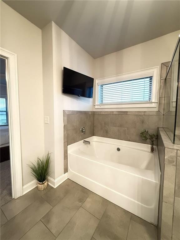 bathroom with tile patterned flooring and a tub