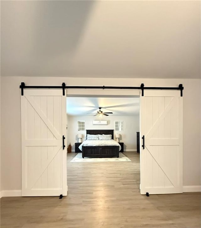 bedroom with hardwood / wood-style flooring, vaulted ceiling, and a barn door