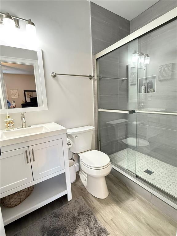 bathroom with vanity, toilet, an enclosed shower, and hardwood / wood-style floors