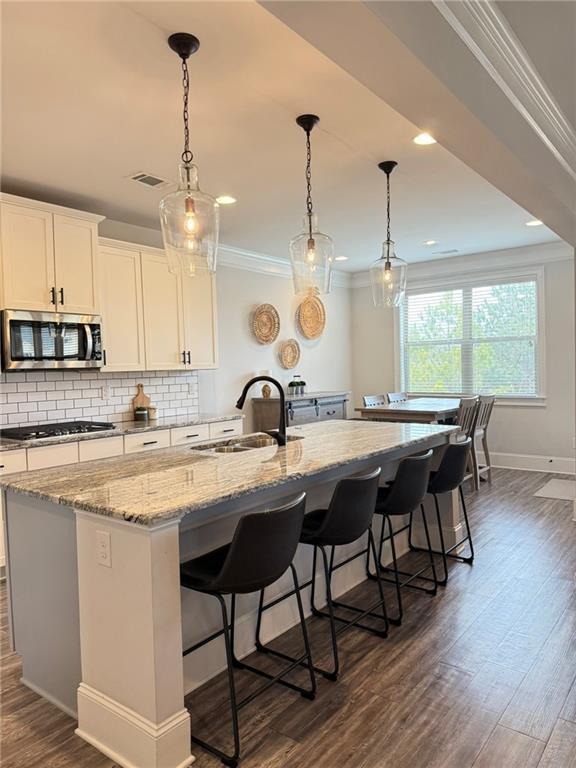 kitchen with white cabinetry, sink, a breakfast bar, and a large island with sink