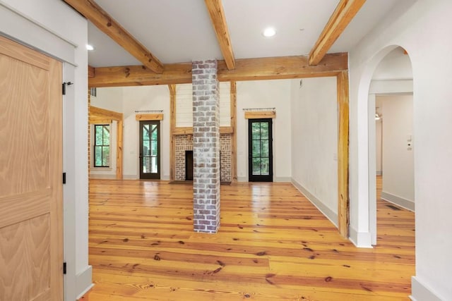 unfurnished living room with beamed ceiling, a brick fireplace, and hardwood / wood-style flooring