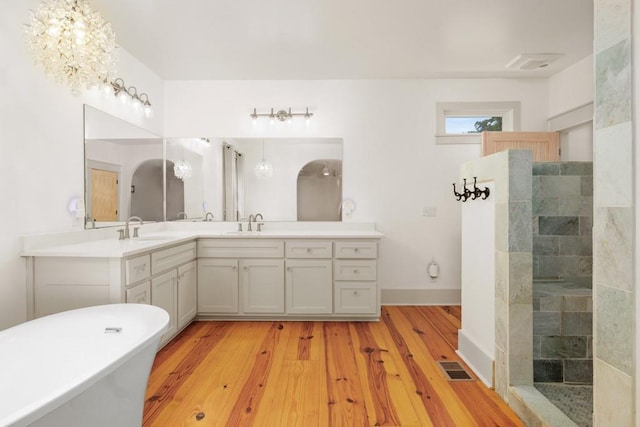 bathroom with vanity, wood-type flooring, shower with separate bathtub, and a chandelier