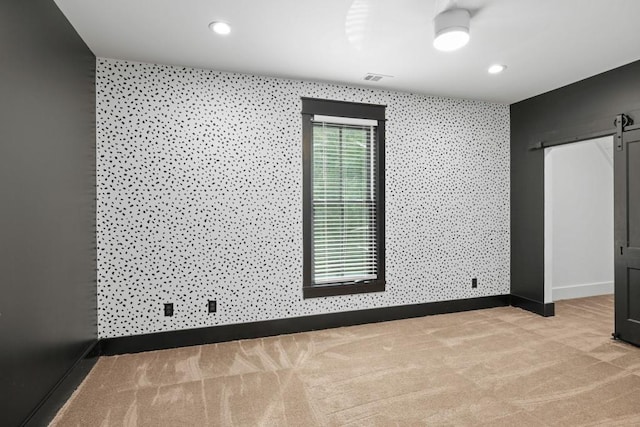 spare room with light colored carpet and a barn door