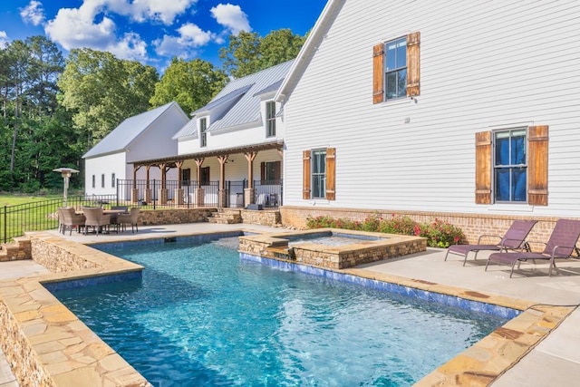 rear view of property featuring a pool with hot tub and a patio area