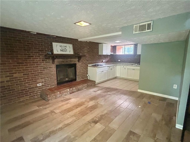 6072 Holiday Blvd, Forest Park, GA 30265 - kitchen with white cabinetry, a fireplace, light countertops, baseboards, and light wood-style floors