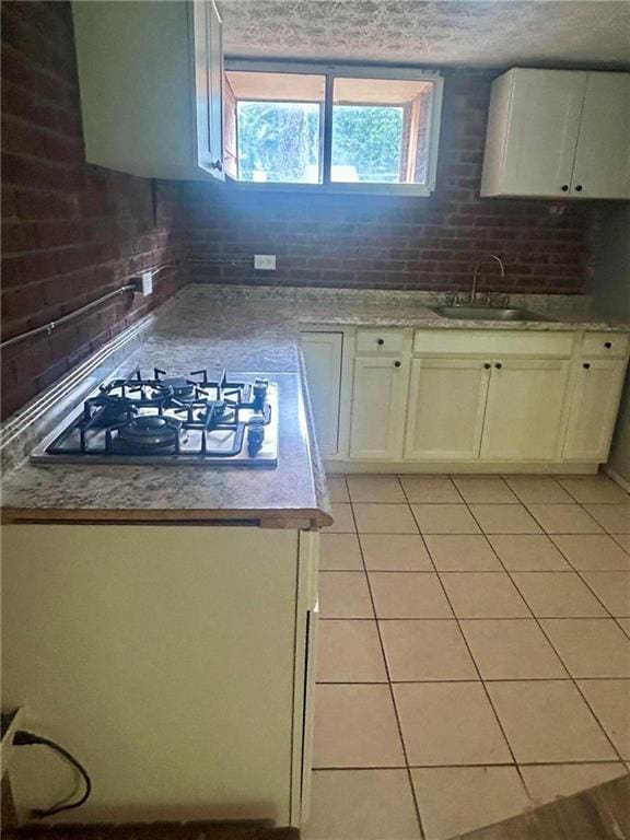 6072 Holiday Blvd, Forest Park, GA 30265 - kitchen with a sink, white gas stovetop, light tile patterned flooring, light countertops, and white cabinets