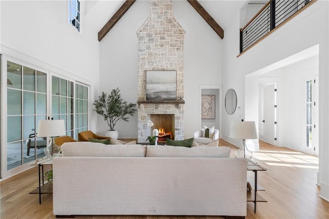 living room featuring a fireplace, beam ceiling, light wood-type flooring, and high vaulted ceiling