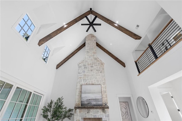 unfurnished living room featuring a fireplace, beam ceiling, and high vaulted ceiling