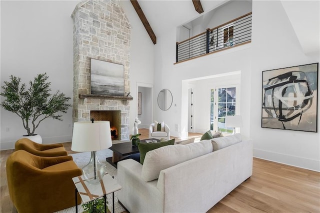 living room with beam ceiling, a stone fireplace, light hardwood / wood-style flooring, and high vaulted ceiling