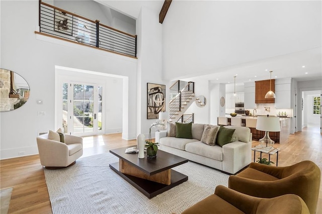 living room featuring beamed ceiling, a high ceiling, and light hardwood / wood-style flooring