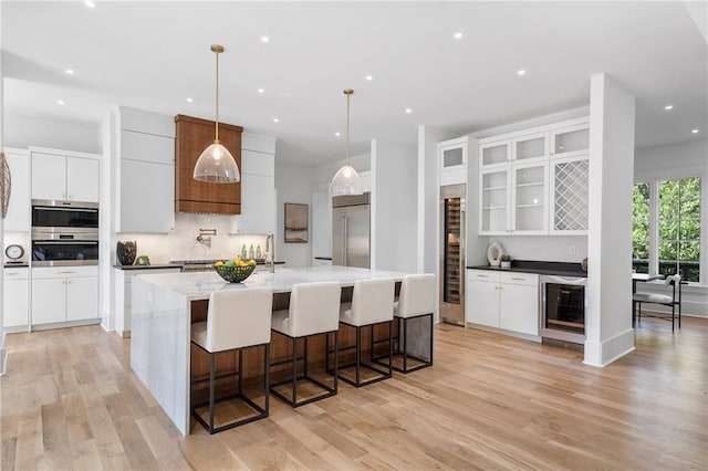 kitchen featuring white cabinets, hanging light fixtures, wine cooler, and built in refrigerator