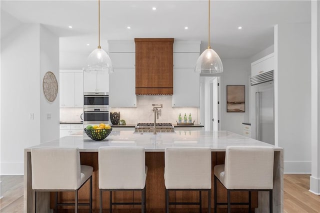 kitchen with decorative light fixtures, white cabinetry, and a large island with sink