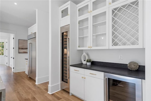 bar with white cabinets, light hardwood / wood-style floors, stainless steel built in fridge, and wine cooler