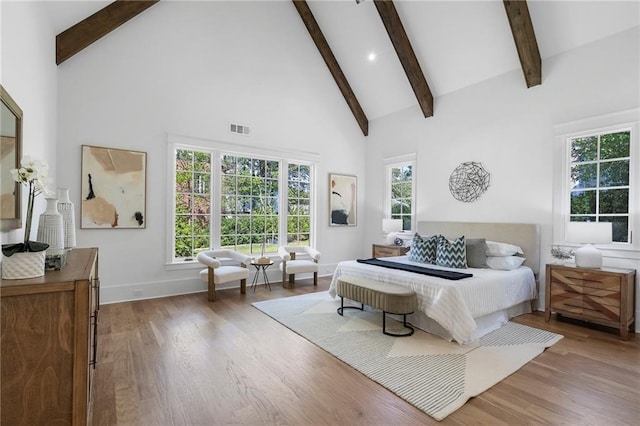 bedroom with beam ceiling, wood-type flooring, and high vaulted ceiling