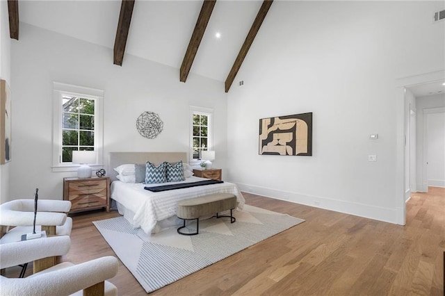 bedroom with beamed ceiling, light hardwood / wood-style floors, and high vaulted ceiling