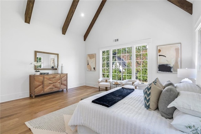 bedroom featuring beamed ceiling, hardwood / wood-style flooring, and high vaulted ceiling