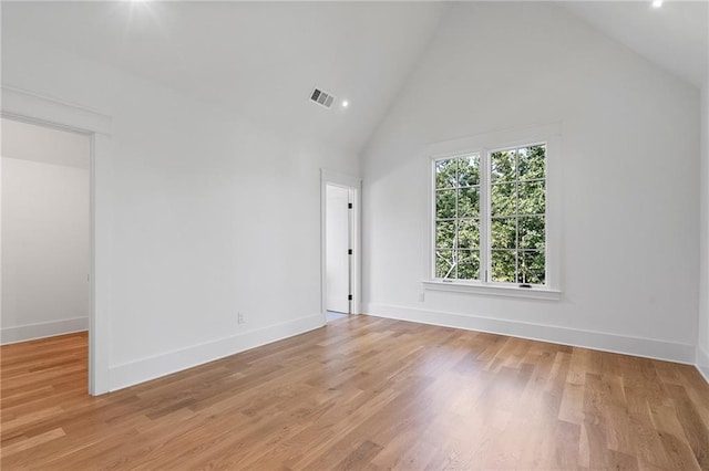 spare room with high vaulted ceiling and light hardwood / wood-style flooring