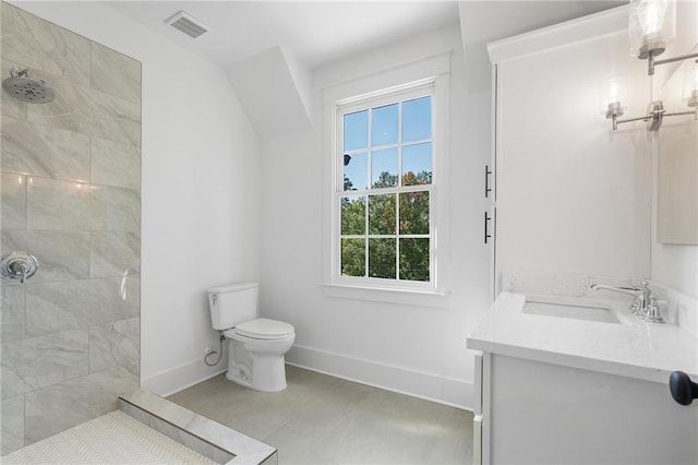 bathroom with vanity, toilet, and a tile shower