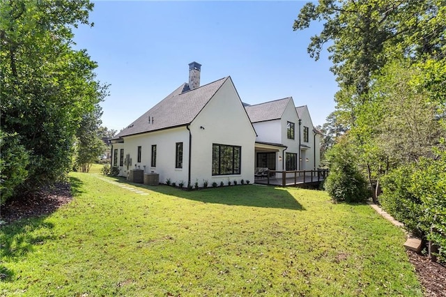 rear view of property with a lawn and central air condition unit