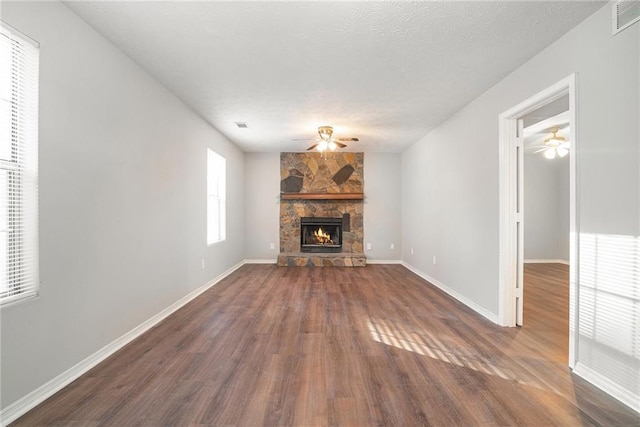 unfurnished living room with a fireplace, a textured ceiling, and dark hardwood / wood-style floors