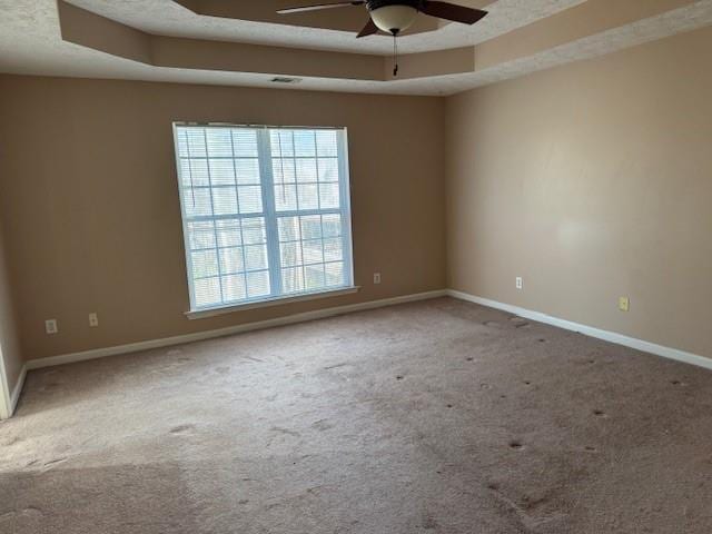 carpeted empty room featuring a tray ceiling and ceiling fan