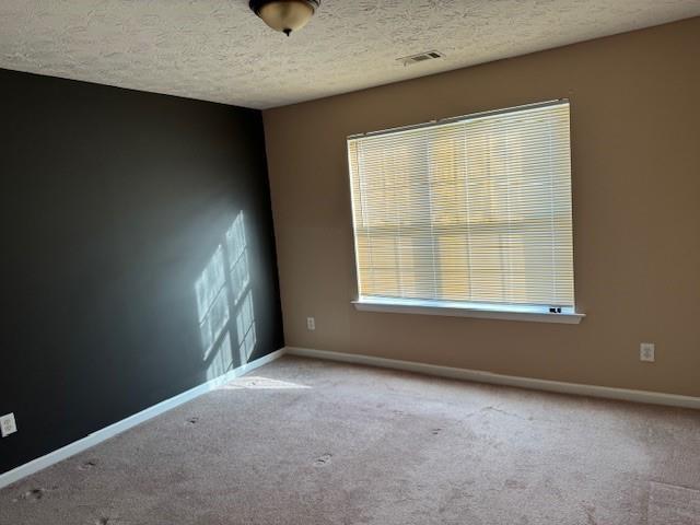 carpeted empty room with a textured ceiling