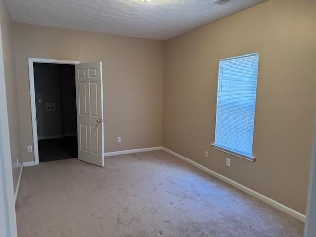 spare room with light carpet and a textured ceiling