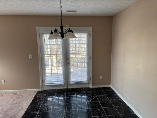 unfurnished dining area featuring dark carpet, a textured ceiling, and an inviting chandelier