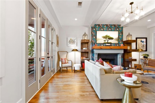 living room featuring beam ceiling, french doors, light hardwood / wood-style flooring, and an inviting chandelier