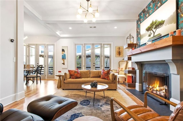 living room featuring beam ceiling, an inviting chandelier, light hardwood / wood-style flooring, and french doors