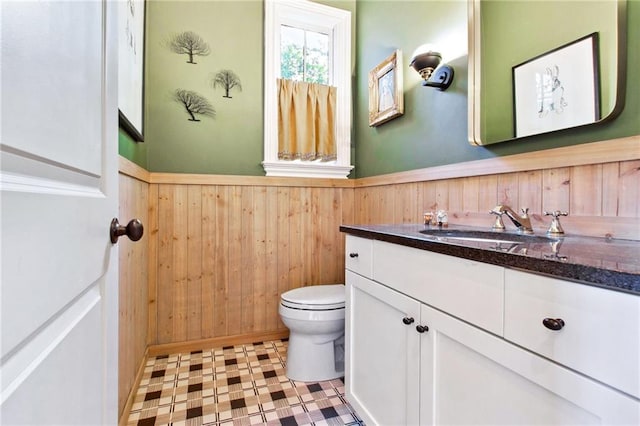 bathroom with an enclosed shower, vanity, wood walls, and toilet