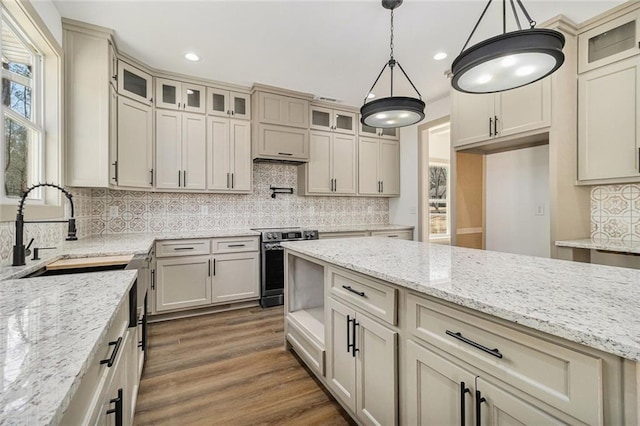 kitchen featuring electric stove, decorative light fixtures, and cream cabinetry