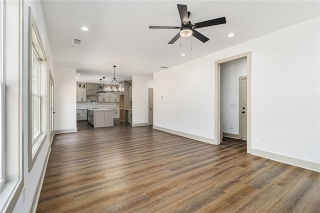 unfurnished living room featuring ceiling fan with notable chandelier and dark hardwood / wood-style flooring