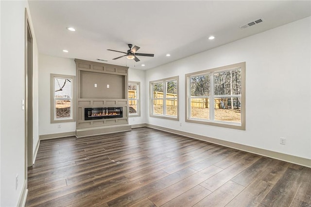 unfurnished living room featuring a fireplace, dark hardwood / wood-style floors, and ceiling fan