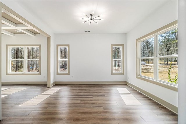 interior space featuring beam ceiling, dark wood-type flooring, and an inviting chandelier