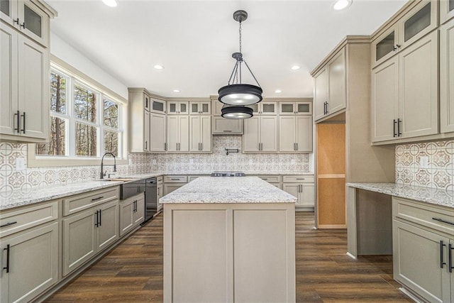 kitchen with light stone counters, dark wood-type flooring, sink, and a kitchen island