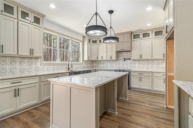 kitchen featuring a center island, sink, light stone counters, and cream cabinetry