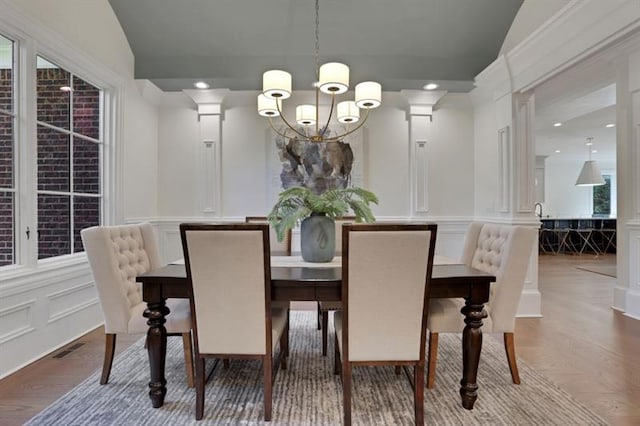 821 Camden Park Ct, Atlanta, GA 30342 - dining area with a decorative wall, a chandelier, wood finished floors, vaulted ceiling, and wainscoting