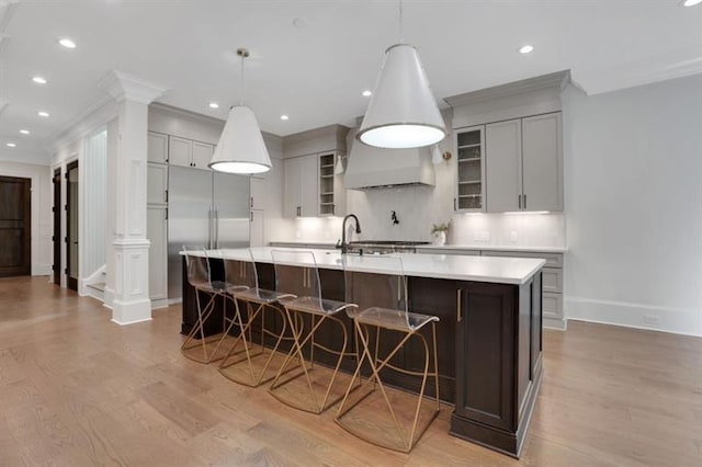 821 Camden Park Ct, Atlanta, GA 30342 - kitchen with crown molding, a large island with sink, built in refrigerator, light countertops, and light wood-type flooring