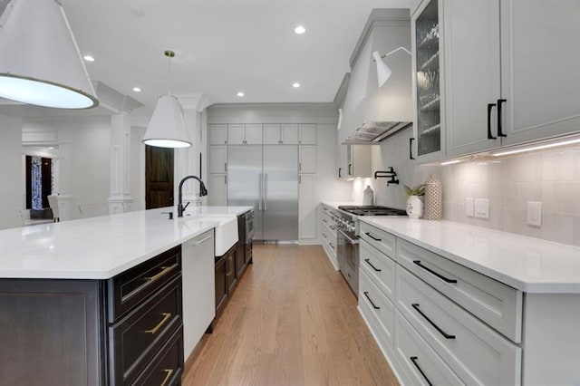 821 Camden Park Ct, Atlanta, GA 30342 - kitchen featuring high quality appliances, premium range hood, light wood-style floors, light countertops, and glass insert cabinets