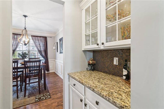 interior space featuring dark wood-type flooring, white cabinets, light stone counters, and decorative light fixtures