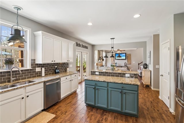 kitchen featuring stainless steel appliances, white cabinetry, sink, and decorative light fixtures