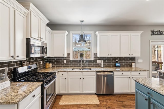 kitchen featuring pendant lighting, sink, blue cabinetry, appliances with stainless steel finishes, and white cabinets