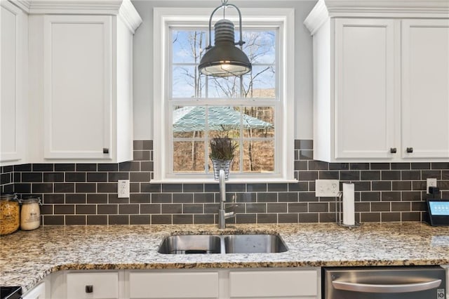 kitchen featuring sink, stainless steel dishwasher, white cabinets, and light stone counters