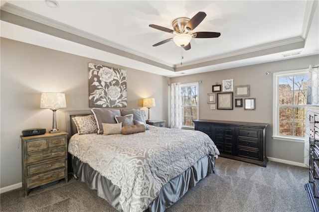 bedroom with ornamental molding, a tray ceiling, multiple windows, and dark colored carpet